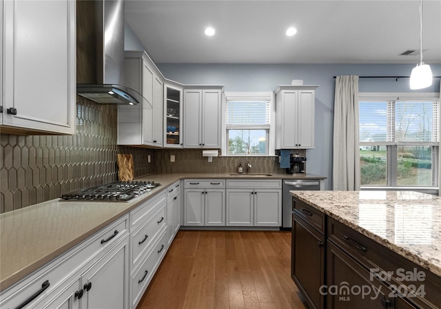 kitchen featuring wall chimney exhaust hood, a wealth of natural light, wood-type flooring, and appliances with stainless steel finishes