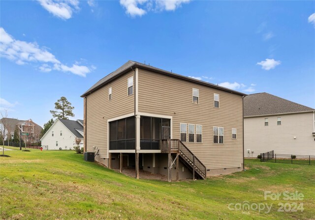 back of property featuring central air condition unit, a sunroom, and a yard