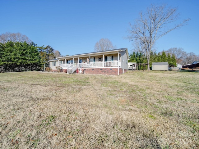 view of front of home with covered porch, a front yard, and a storage shed