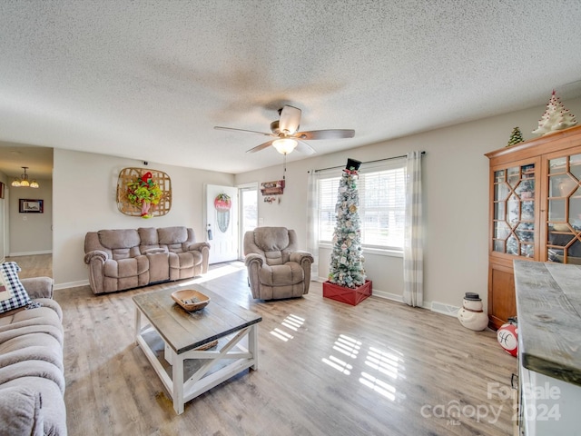 living room featuring a textured ceiling, light hardwood / wood-style flooring, and ceiling fan with notable chandelier