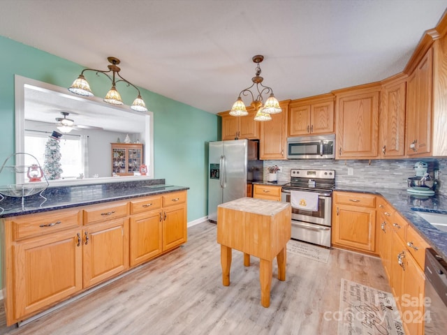 kitchen with ceiling fan with notable chandelier, stainless steel appliances, decorative light fixtures, and light wood-type flooring