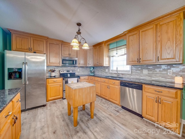 kitchen featuring sink, stainless steel appliances, light hardwood / wood-style flooring, pendant lighting, and decorative backsplash