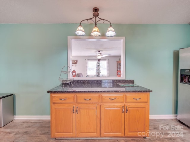 kitchen featuring stainless steel fridge, light wood-type flooring, ceiling fan, and pendant lighting