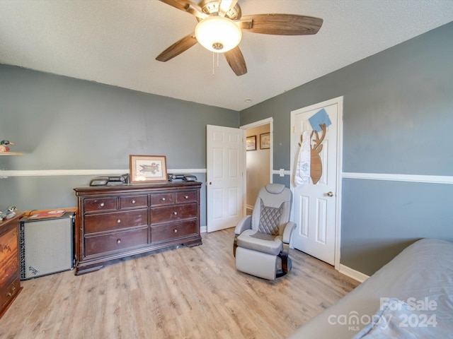 bedroom with ceiling fan, light hardwood / wood-style floors, and a textured ceiling