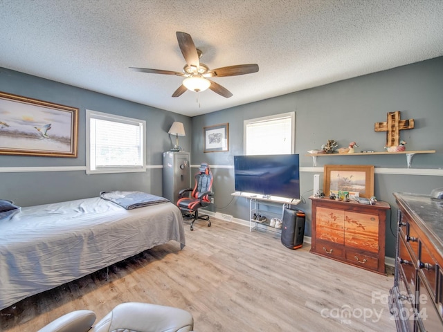 bedroom featuring ceiling fan, light hardwood / wood-style flooring, and a textured ceiling