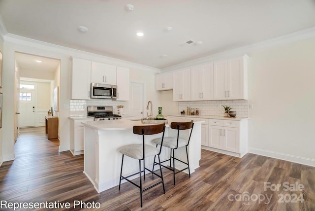 kitchen with ornamental molding, stainless steel appliances, white cabinets, dark hardwood / wood-style floors, and an island with sink