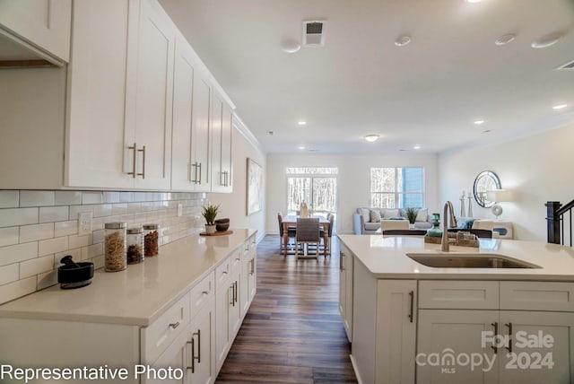 kitchen featuring ornamental molding, a kitchen island with sink, sink, dark hardwood / wood-style floors, and white cabinetry