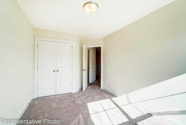 unfurnished bedroom featuring light colored carpet and a closet