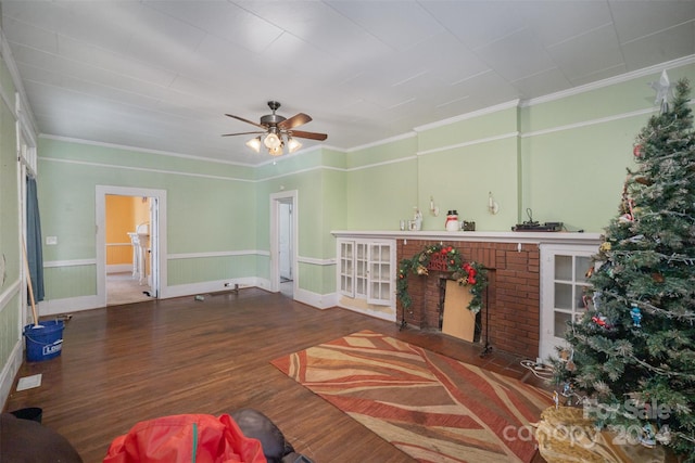 living room featuring ceiling fan, wood-type flooring, a fireplace, and ornamental molding