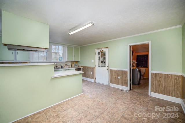 kitchen with kitchen peninsula, wooden walls, crown molding, and a textured ceiling