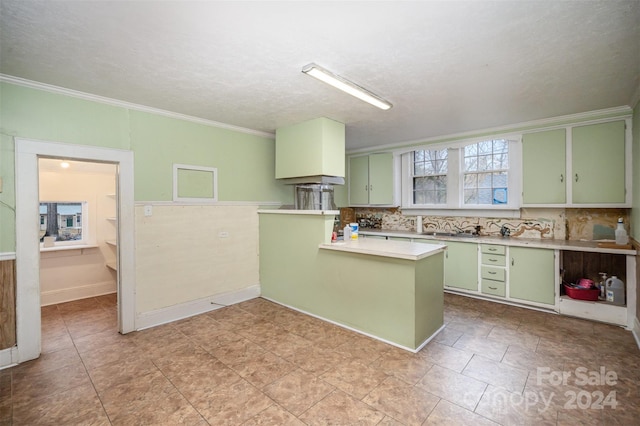 kitchen featuring tasteful backsplash, kitchen peninsula, crown molding, and green cabinetry