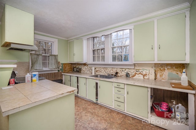 kitchen featuring light tile patterned floors, green cabinets, crown molding, and sink