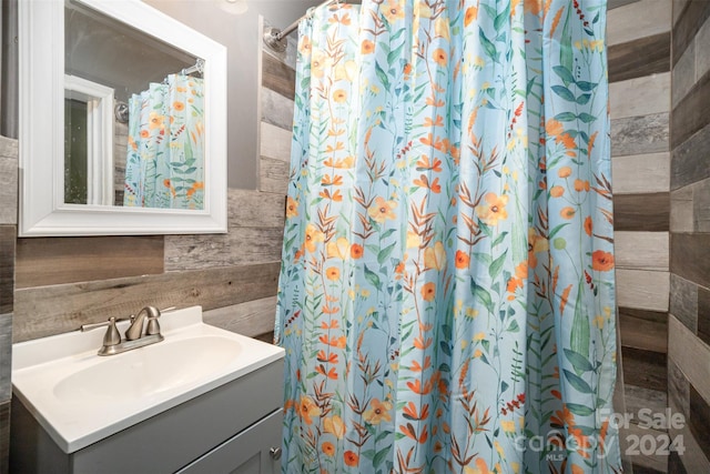 bathroom featuring a shower with shower curtain, vanity, and tile walls