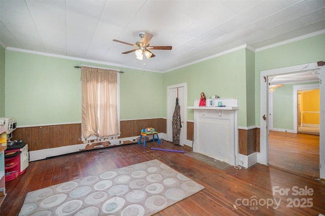 miscellaneous room featuring dark wood-type flooring, ceiling fan, ornamental molding, and wooden walls