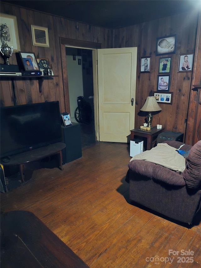 living room featuring dark hardwood / wood-style flooring and wooden walls