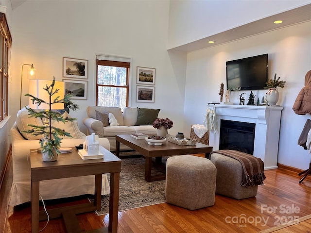 living room with a towering ceiling and wood-type flooring