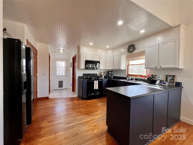 kitchen with sink, black appliances, light hardwood / wood-style flooring, kitchen peninsula, and white cabinets