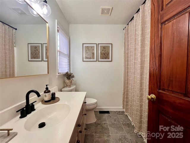 bathroom with vanity, toilet, and a textured ceiling