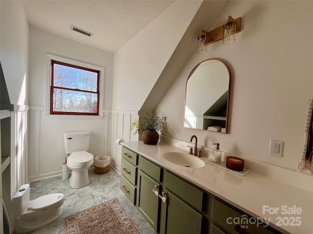 bathroom with vanity, a textured ceiling, and toilet