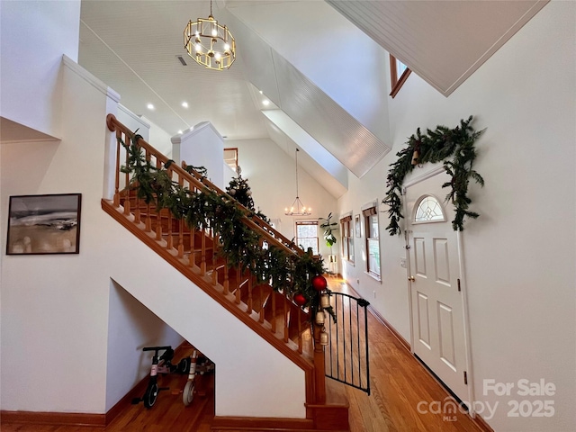 entryway with hardwood / wood-style flooring, a towering ceiling, and a notable chandelier