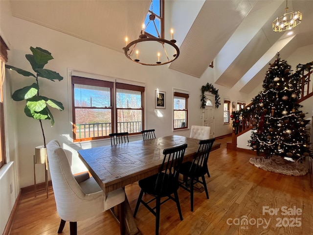 dining space featuring light hardwood / wood-style floors, high vaulted ceiling, and a notable chandelier