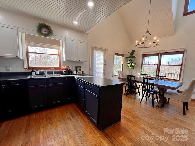 kitchen featuring black dishwasher, sink, white cabinets, and decorative light fixtures