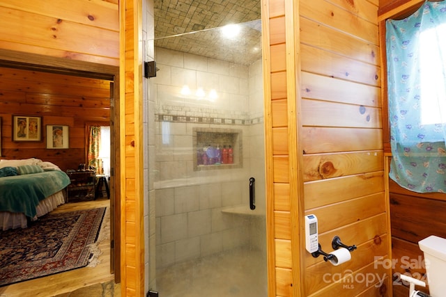 bathroom with an enclosed shower, toilet, wood-type flooring, and wooden walls