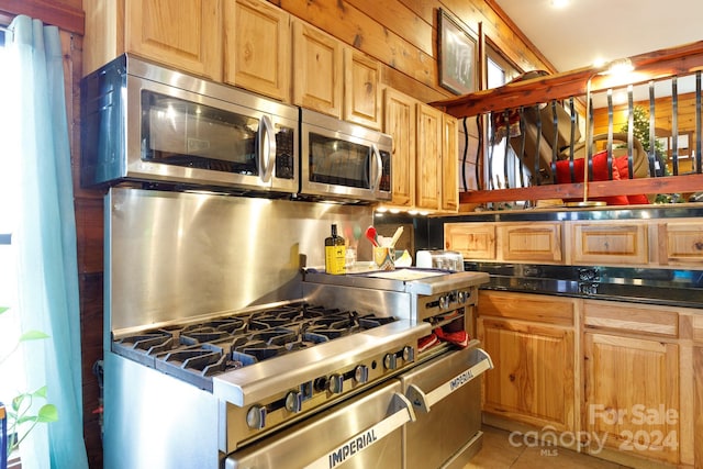 kitchen featuring light tile patterned floors, backsplash, stainless steel appliances, and wood walls