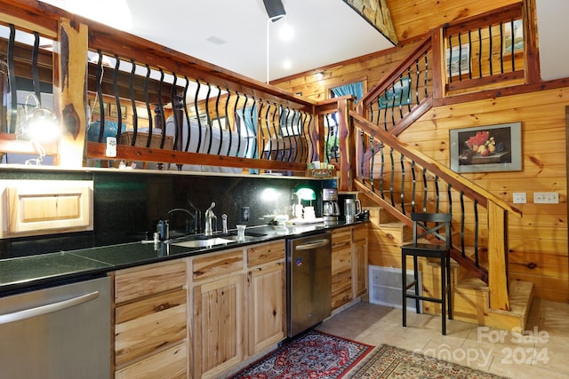 kitchen with dishwasher, wood walls, and light brown cabinets