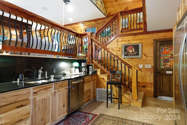 kitchen with appliances with stainless steel finishes, light brown cabinets, light tile patterned floors, and wooden walls