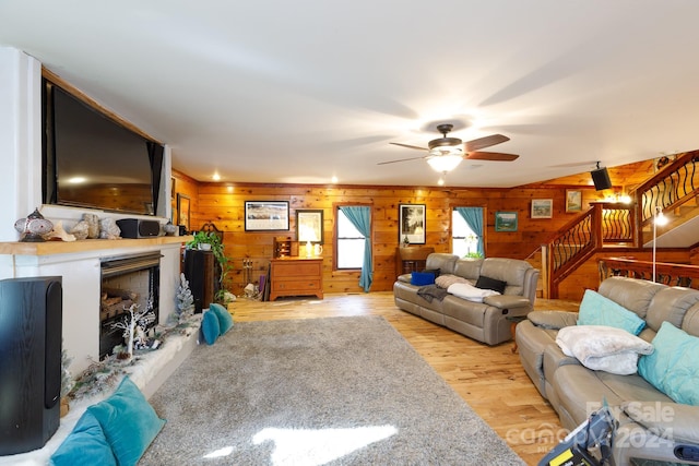 living room featuring light hardwood / wood-style floors, ceiling fan, and wood walls