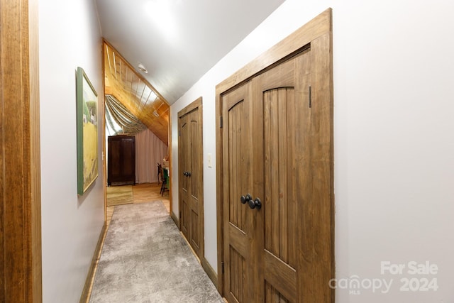 hall with light colored carpet and lofted ceiling