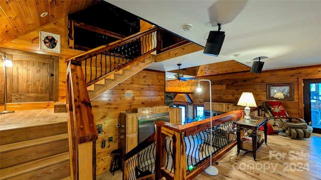 staircase with hardwood / wood-style floors, a wealth of natural light, lofted ceiling, and wood walls