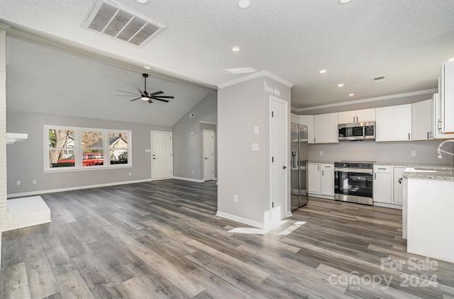 kitchen featuring hardwood / wood-style floors, white cabinets, stainless steel appliances, and lofted ceiling