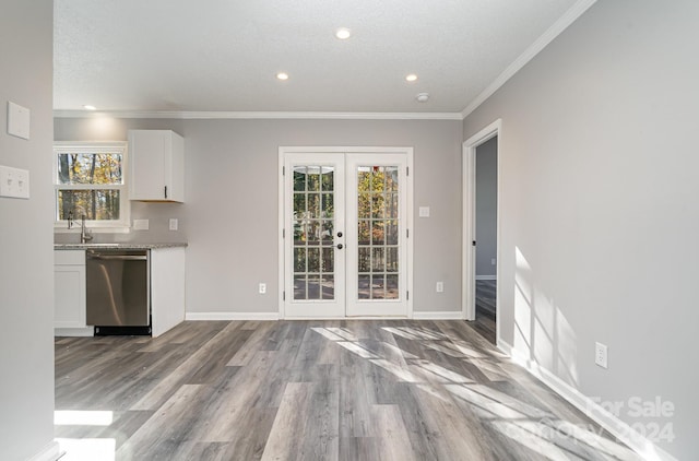 interior space with a healthy amount of sunlight, french doors, white cabinets, and stainless steel dishwasher