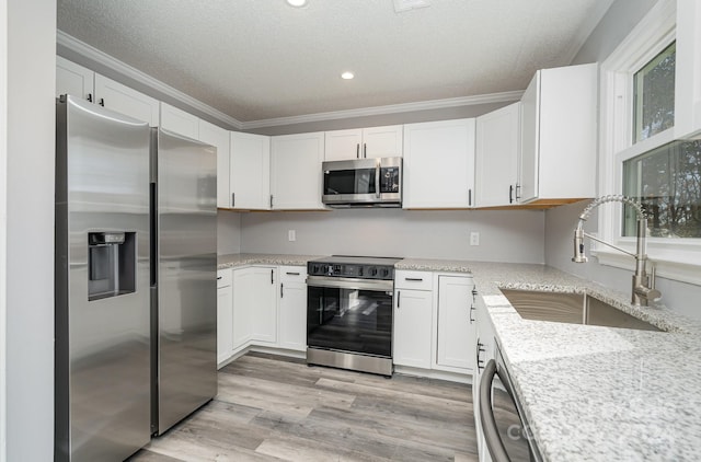 kitchen with stainless steel appliances, white cabinetry, crown molding, and sink