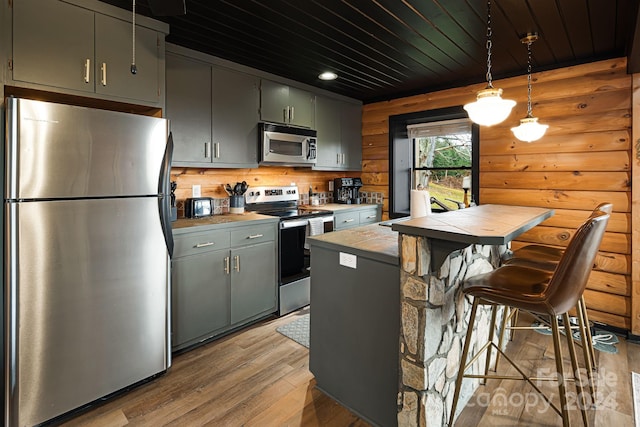 kitchen featuring wooden ceiling, hanging light fixtures, stainless steel appliances, tile countertops, and light hardwood / wood-style floors