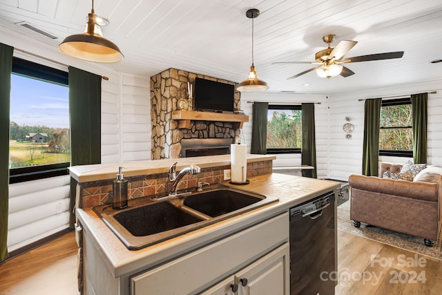 kitchen with light hardwood / wood-style floors, a center island with sink, a healthy amount of sunlight, and black dishwasher