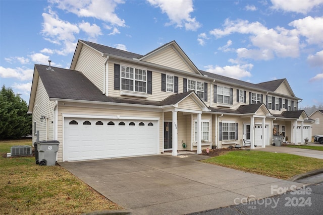 view of front facade with a front lawn, a garage, and cooling unit