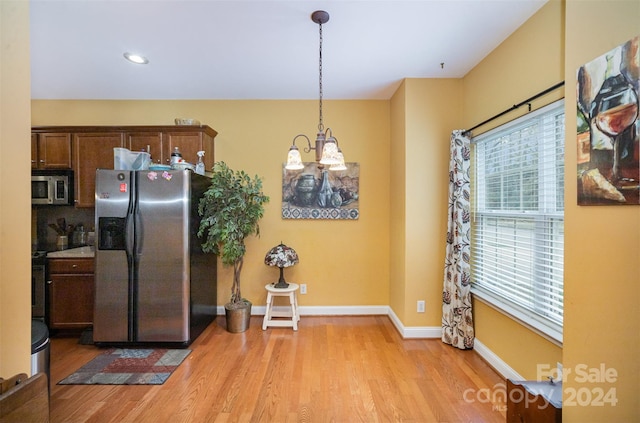 kitchen featuring a chandelier, hanging light fixtures, appliances with stainless steel finishes, and light hardwood / wood-style flooring