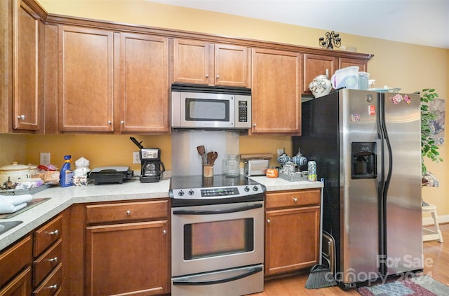 kitchen featuring appliances with stainless steel finishes and light hardwood / wood-style flooring