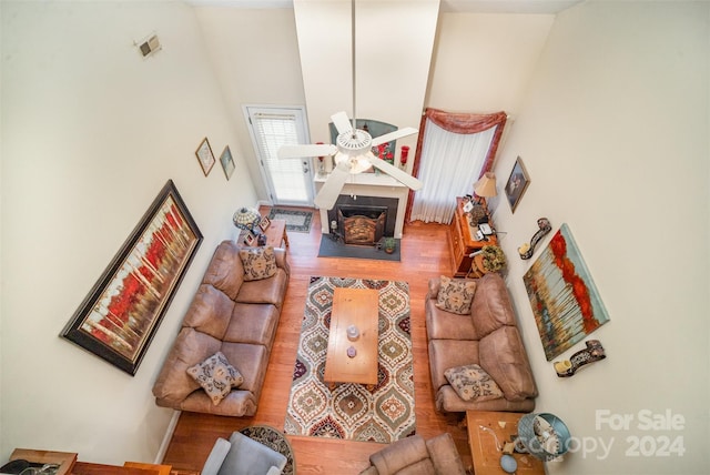 living room featuring ceiling fan, wood-type flooring, and a towering ceiling