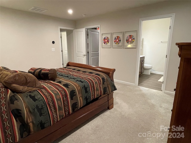 bedroom with light carpet and connected bathroom