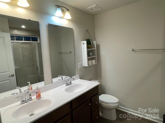 bathroom with hardwood / wood-style floors, vanity, toilet, and walk in shower