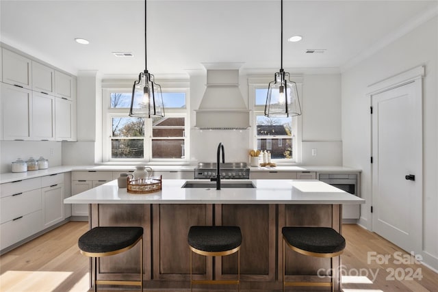 kitchen with plenty of natural light, light hardwood / wood-style floors, a kitchen island with sink, and a breakfast bar area