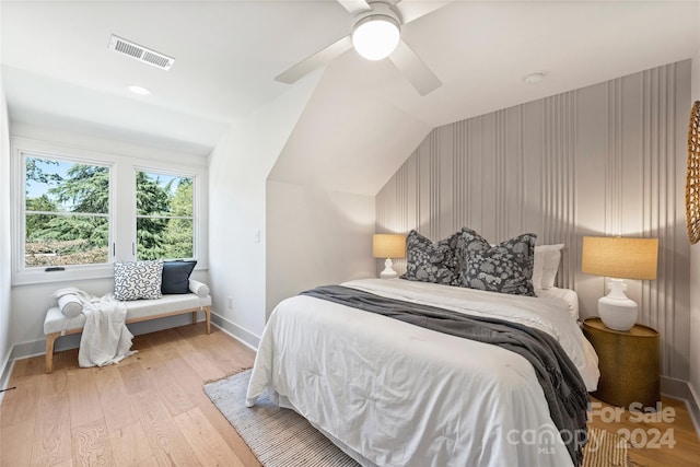 bedroom with ceiling fan, light hardwood / wood-style floors, and vaulted ceiling