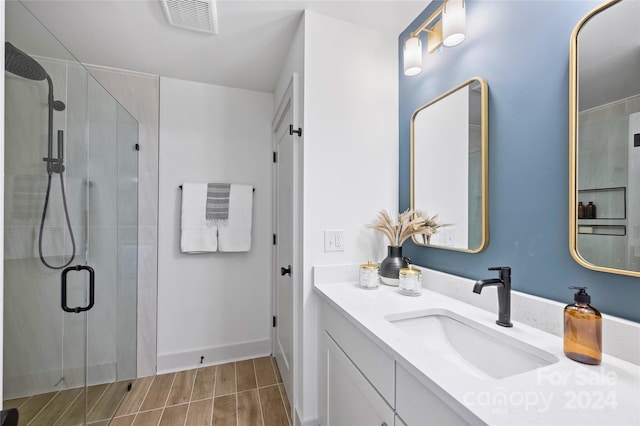 bathroom with hardwood / wood-style flooring, vanity, and a shower with shower door