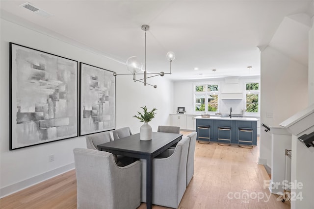 dining space with light hardwood / wood-style floors, sink, and a chandelier