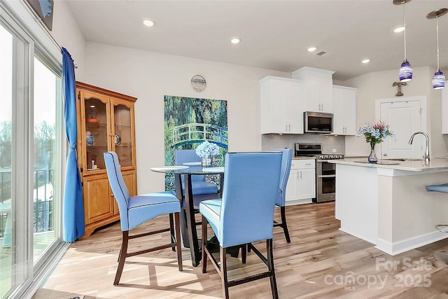 kitchen with sink, decorative light fixtures, stainless steel appliances, and white cabinets