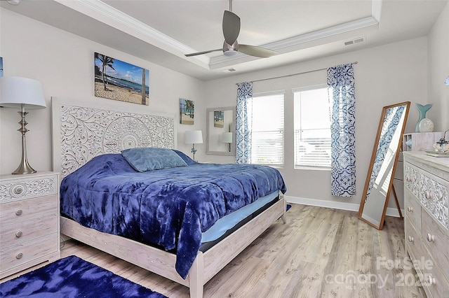 bedroom featuring light hardwood / wood-style flooring, ornamental molding, a raised ceiling, and ceiling fan